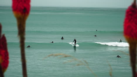 People-enjoy-surfing-on-calm-ocean-waves-at-Riverton,-New-Zealand