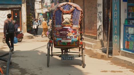 Vista-Del-Paisaje-Urbano-De-Una-Colorida-Bicicleta-Rickshaw-Tradicional-En-Una-Calle-Muy-Transitada-En-Katmandú,-Nepal