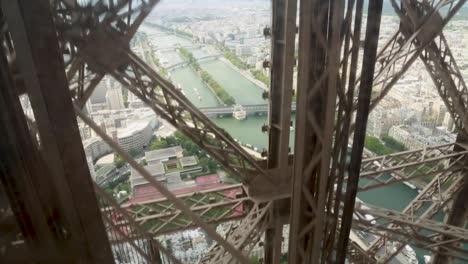 Camera-shot-inside-the-Eiffel-Tower-elevator-descending-with-the-Seine-River-in-the-background,-Paris,-France