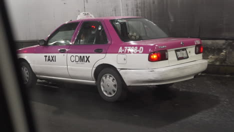Blick-Aus-Dem-Fahrzeugfenster-Auf-Ein-Typisch-Mexikanisches-Rosafarbenes-Taxi,-Das-Durch-Einen-Tunnel-Fährt