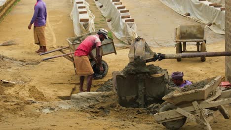 Workers-Digging-up-Mud-and-Clay-with-Bare-Hands-and-Tossing-it-in-Wheelbarrows-in-a-Brick-Factory-in-Bangladesh