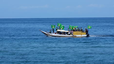 People-holding-political-party-flags-on-a-local-boats-for-upcoming-election-campaign-2023-in-Timor-Leste,-Southeast-Asia