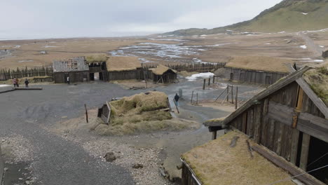 Drone-Shot-of-Viking-Village,-Wooden-Buildings-and-Tourists-in-Abandoned-Movie-Set