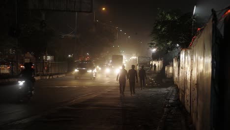 Starker-Verkehr-In-Der-Nacht-In-Neu-Delhi,-Indien,-Menschen-Gehen-Neben-Der-Straße