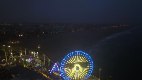 Drone-shot-over-the-Santa-Monica-pier-and-over-a-misty-beach,-in-Los-Angeles,-USA