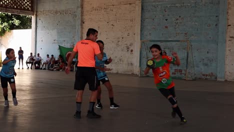 Das-Handballspiel-Der-Mädchen-In-Zeitlupe,-Ein-Mädchen-Wird-Verfolgt,-Während-Sie-Den-Ball-Hat-Und-Ihn-Ihrer-Mitspielerin-Zuspielt