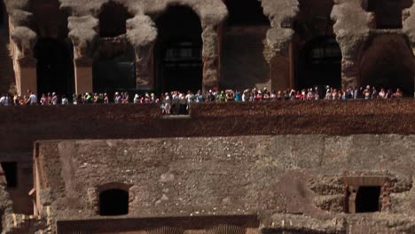 Inside-view-of-the-Roman-Colosseum-with-large-crowd-of-visitors-walking-in-the-distance,-Rome,-Italy