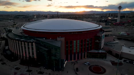 Half-aerial-orbit-around-Ball-Arena-in-Denver,-vivid-sunset-sky