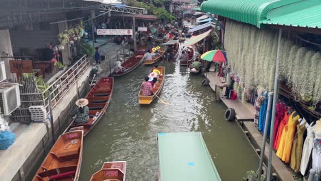 Tourists-enjoy-the-boat-ride-in-Damnoen-Saduak-Floating-Market,-the-vibrant-atmosphere-and-colourful-scenery-in-Ratchaburi-province,-South-West-of-Bangkok,-Thailand