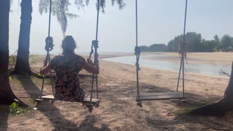 Female-tourist-uses-Palm-Tree-swings-on-beach-in-paradise