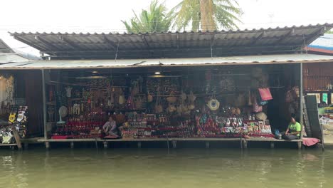 Vista-Frontal-De-Los-Puestos-De-Souvenirs-En-El-Mercado-Flotante-Damnoen-Saduak,-Provincia-De-Ratchaburi,-Al-Suroeste-De-Bangkok,-Tailandia
