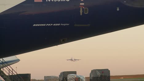 Nahaufnahme-Eines-Blauen-Frachtflugzeugs,-In-Der-Ferne-Startet-Ein-Großes-Frachtflugzeug