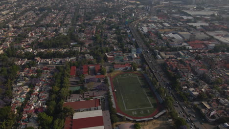 Vista-Panorámica-Aérea-Panorama-De-Edificios-Del-Paisaje-Urbano-De-México-Con-Vehículos-En-El-Tráfico-Pesado-De-La-Ciudad-Y-Estadio-En-Verano