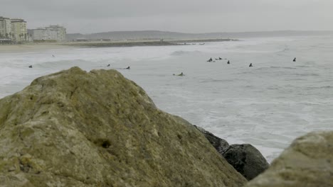 Group-of-surfers-waiting-for-the-best-wave-pov-behind-the-rocks