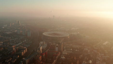Dolly-forward-aerial-shot-towards-Arsenal-football-Stadium-backlit-by-the-sun