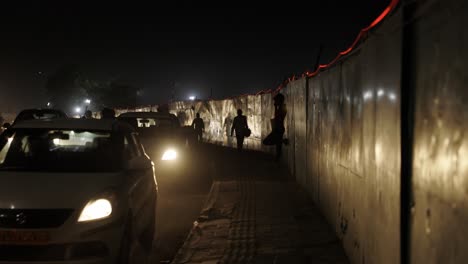 Tráfico-Intenso-Por-La-Noche-En-Nueva-Delhi,-India,-Gente-Caminando-Y-Esperando