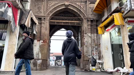 People-are-walking-in-old-city-rasht-in-gilan-market-bazaar-down-town-concept-grocery-and-foods-and-a-girl-walking-to-an-ancient-historical-gate-of-caravanserai-traditional-architecture-design-arche