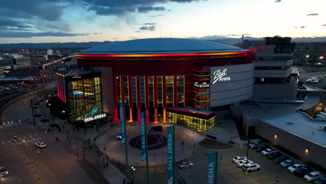 Twilight-aerial-pullback-of-Ball-Arena-in-Denver,-colorful-lighting-on-exterior