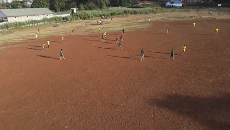 Soccer-game-on-arid-pitch,-local-football-match-in-Loitokitok,-Kenya,-aerial