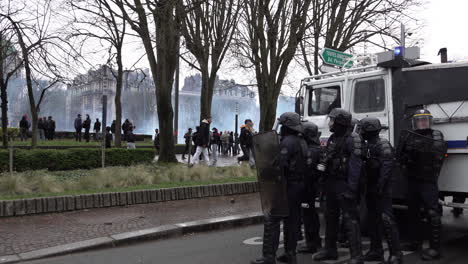 Eine-Einheit-Maskierter-Bereitschaftspolizisten-Steht-Neben-Einem-Wasserwerfer-Lastwagen,-Nachdem-Während-Der-Landesweiten-Streikaktion-Und-Den-Protesten-Gegen-Eine-Anhebung-Des-Rentenalters-Tränengas-Auf-Demonstranten-Abgefeuert-Wurde
