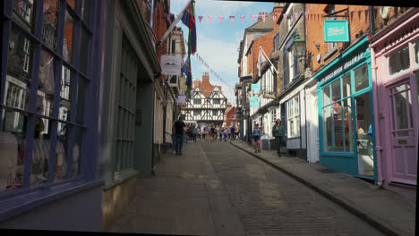 Tourists-and-shoppers-walking-around-the-ancient-and-historic-city-of-Lincoln,-Showing-medieval-streets-and-buildings