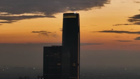 Aerial-parallax-around-the-Torre-Mítikah-Tower,-dramatic-evening-in-Mexico-city