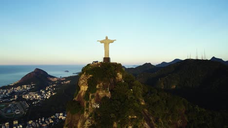 Aerial-view-around-the-Christ-The-Redeemer-statue,-revealing-the-city-of-Rio-de-Janeiro,-sunset-in-Brazil