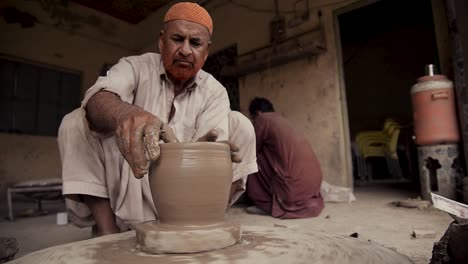 A-old-experienced-man-crafting-a-clay-vessel-on-a-potter's-wheel
