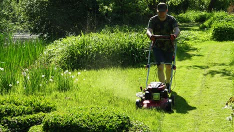 The-young-male-is-moving-a-lawn-during-s-sunny-summer-day-of-2023-4K-footage-Lithuania