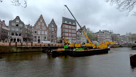 View-Of-Floating-Barge-Crane-On-Amsterdam-Canal-For-Canal-Strengthening-Works-On-Overcast-Day
