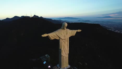 Aerial-view-away-from-the-Christ-the-Redeemer-statue,-sunset-in-Rio,-Brazil---pull-back,-drone-shot
