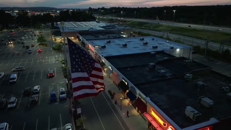 American-flag-waving-at-dark-shopping-center-in-USA-at-night
