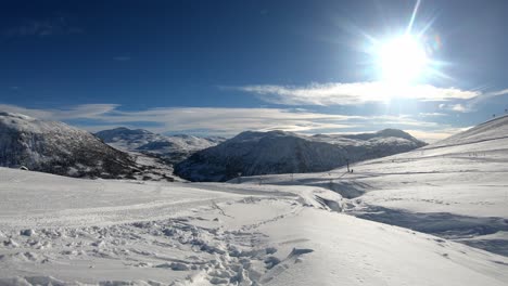 Stunning-winter-scenery-in-Skiing-destination-Myrkdalen---Sunny-winter-day-from-mountain-skiing-resort-with-Myrkdalen-valley-seen-behind---Slow-push-in-and-skiers-in-far-background