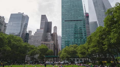 timelapse-of-bryant-park-in-new-york-by-day-with-people-walking,-eating-and-enjoying-downtown-manhattan,-with-skyscrapers-all-around-and-clouds-passing-by
