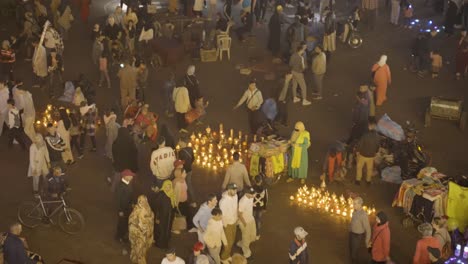 Vendors-Selling-Illuminated-Oil-Lamps-On-The-Ground-In-Crowded-Marketplace-In-Marrakech,-Morocco-At-Night