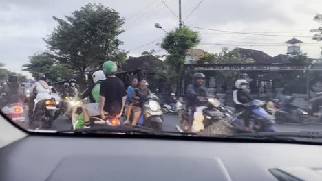 Driving-in-a-van-through-hundreds-of-motorbikes-in-heavy-midday-traffic-on-the-island-of-Bali,-Indonesia-near-Canggu