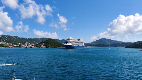 In-the-foreground,-a-magnificent-cruise-ship-takes-center-stage,-while-in-the-backdrop,-a-stunning-Caribbean-island-reveals-its-natural-splendor