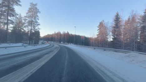 The-car-glided-along-the-winter-road,-with-pine-trees-lining-the-sides,-their-branches-adorned-with-snow,-creating-a-picturesque-winter-wonderland