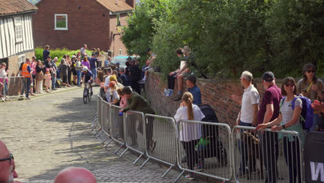 Cyclists-racing-in-the-in-the-famous-and-historic-city-of-Lincoln,-Showing-medieval-streets-and-buildings