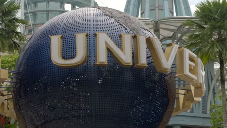 Universal-studio-Singapore-sign-orbiting-shot-between-palm-trees-at-afternoon