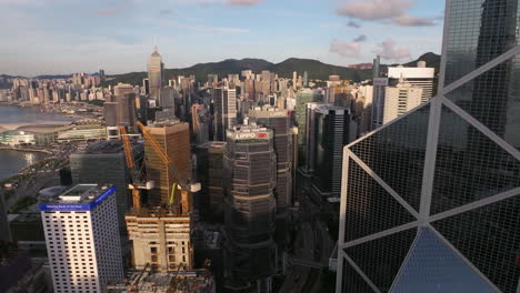 Aerial-view-rising-along-the-Bank-of-China-tower,-overlooking-high-rise-office-towers-in-sunny-Central,-Hong-Kong