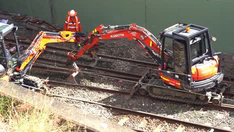 Construction-workers-working-on-Cross-River-Rail-transport-network-project-in-Brisbane,-Queensland,-Australia,-excavators-digging-ballast-off-the-trackbed-onsite,-close-up-shot
