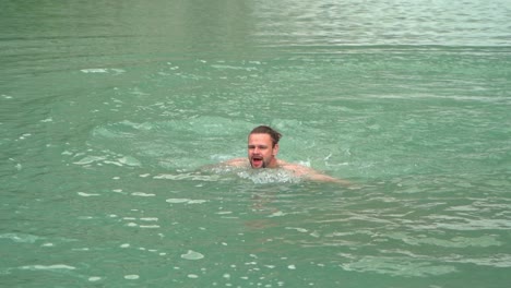 Tough-man-swimming-in-Norwegian-glacial-water-below-Jostedal-glacier-during-summer-vacation---Slow-motion