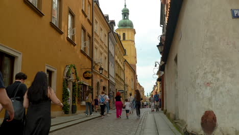Tourists-walk-along-Piwna-street-in-Warsaw-near-the-Castle-Square,-Sigismund's-Column