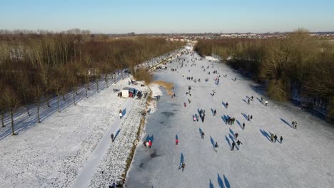 Revealing-drone-shot-of-a-large-group-of-people-skating-on-natural-ice-in-Tiel