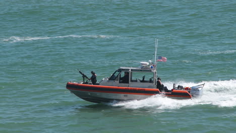 Experience-the-power-of-the-US-Coast-Guard-in-action-as-their-boat-charges-through-the-ocean,-soldier-and-machine-gun-in-tow-