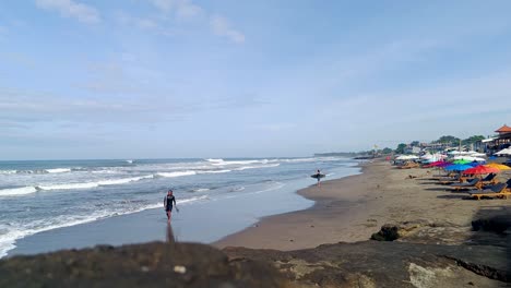 Ein-Mann-Nach-Dem-Surfen-Mit-Einem-Surfbrett-Am-Strand-Von-Canggu,-Bali,-Indonesien,-Asien