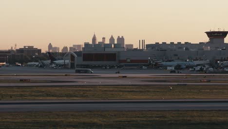 A-Delta-commercial-airplane-taxis-by-the-ATL-airport-with-the-Atlanta-Georgia-skyline-in-the-background-in-the-evening