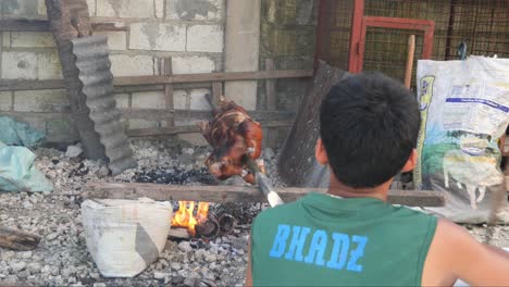 April-22,-2023-Danao-City,-Cebu,-Philippines---A-Man-is-Roasting-a-Lechon-Baboy-or-Suckling-Pig-with-a-Crispy-Red-Skin-over-a-Charcoal-Fire-in-a-Local-Backyard