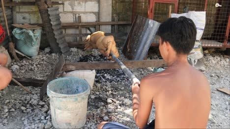 April-22,-2023-Danao-City,-Cebu,-Philippines---A-Man-is-Roasting-a-Lechon-Baboy-or-Suckling-Pig-over-a-Charcoal-Fire-in-a-Local-Backyard
